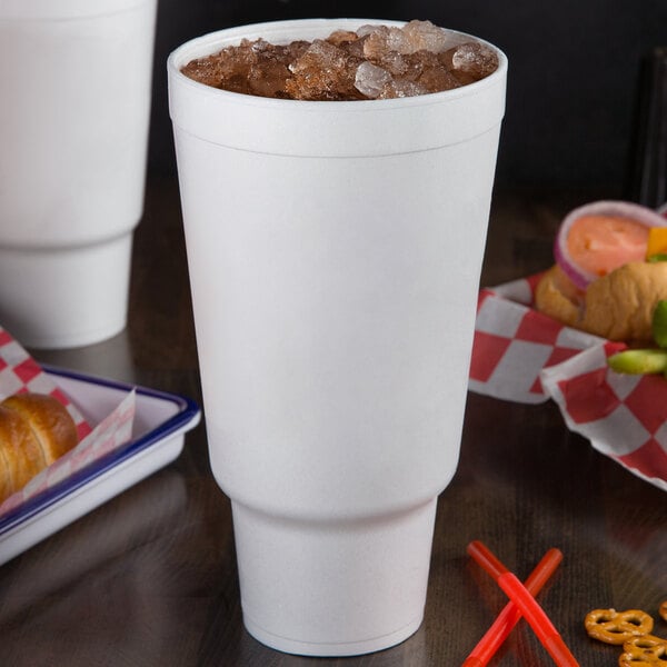A white Dart foam cup on a table with ice in it.