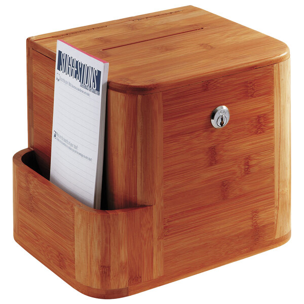 A Safco cherry bamboo suggestion box on a counter with a piece of paper in it.