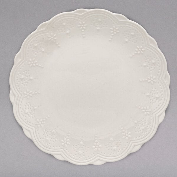 A white 10 Strawberry Street Valentina porcelain plate with a scalloped edge and a pattern on it.