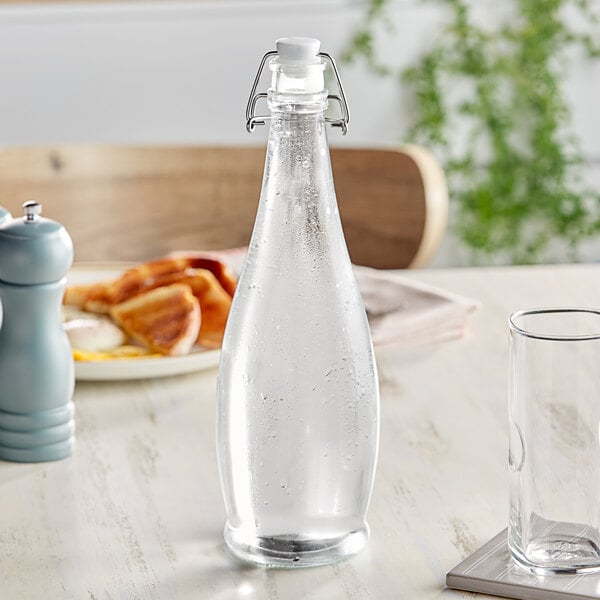 A Libbey glass water bottle with a clear wire bail lid on a table.