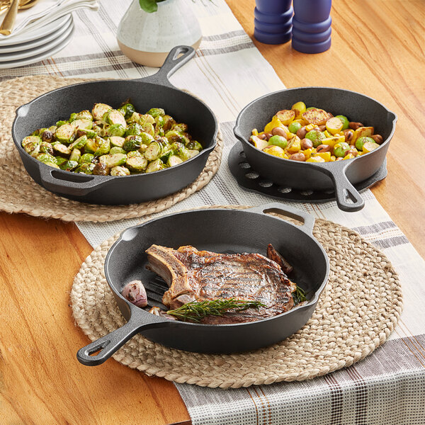 Three Valor pre-seasoned cast iron skillets with steak and vegetables in them.