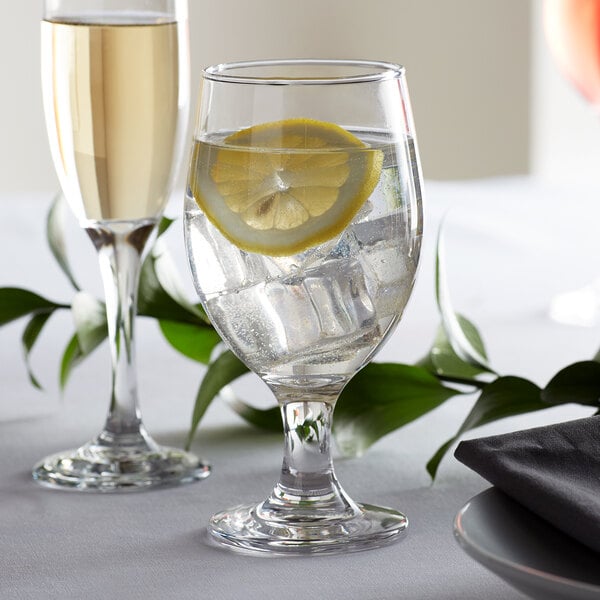 A customizable Acopa glass of water with ice and a lemon slice.