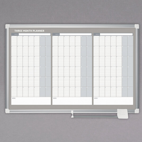 A white MasterVision dry erase board with a calendar for three months.