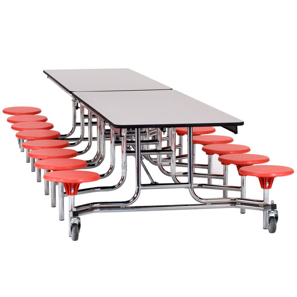 A long National Public Seating cafeteria table with red stools with a black frame and plywood top and T-molding edge.