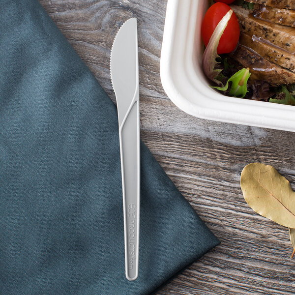 A gray Eco-Products compostable plastic knife next to a container of food.