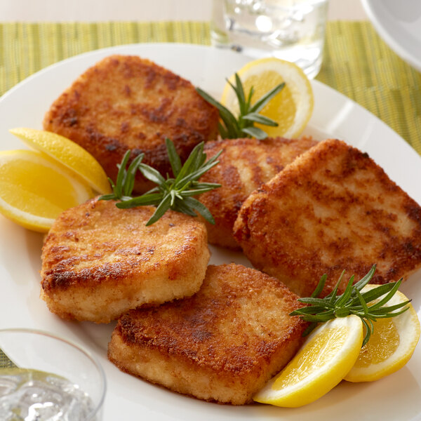 A white plate of Spring Glen Fresh Foods fried lemon risotto cakes with lemon wedges.