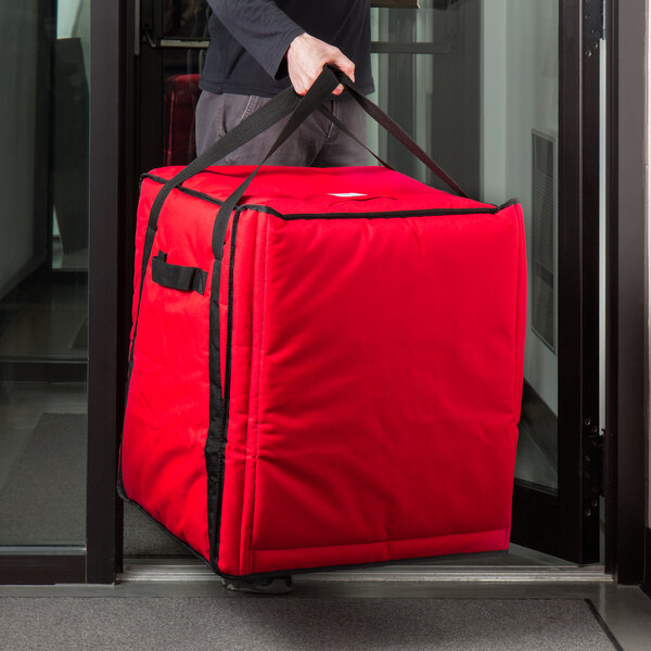 A person holding a large red Cambro pizza delivery bag.
