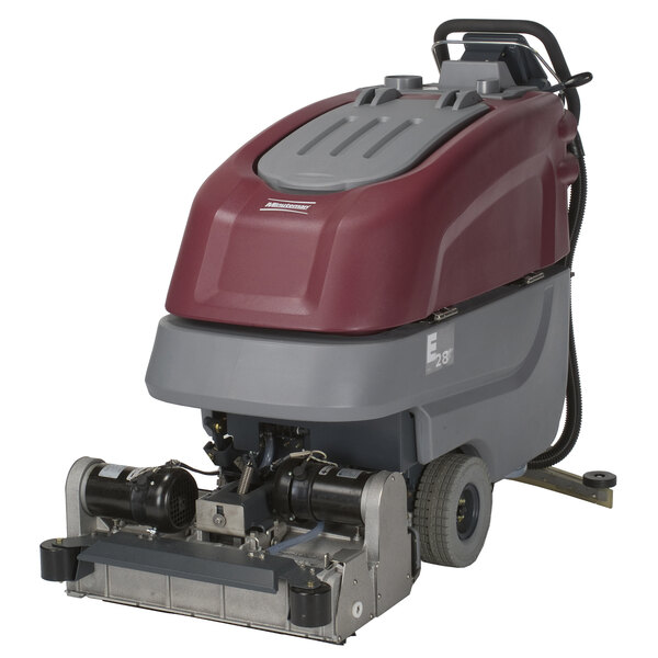 A Minuteman E28 walk behind cylindrical floor scrubber with a red cover and grey wheels.