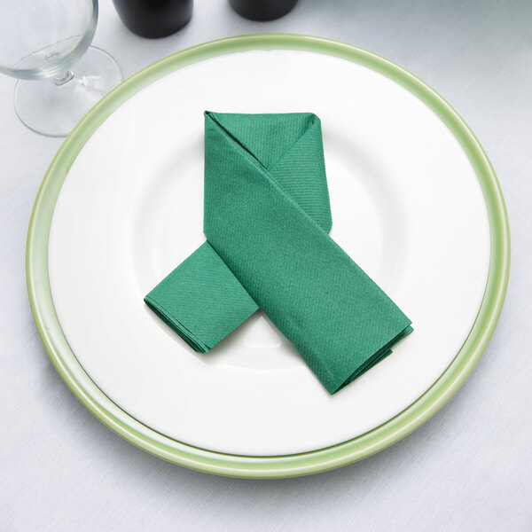 A Hunter green napkin folded on a white plate.