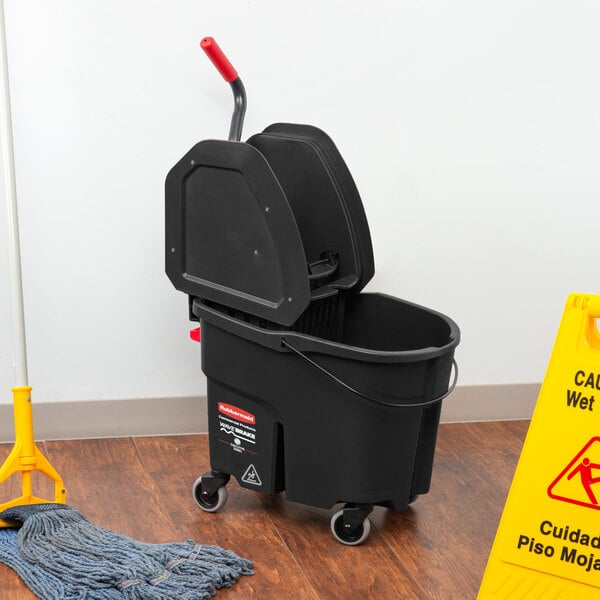 A Rubbermaid black mop bucket with a red wringer on the floor.