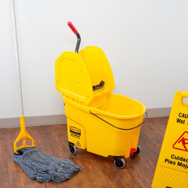 A yellow Rubbermaid mop bucket with wringer on a wood floor.