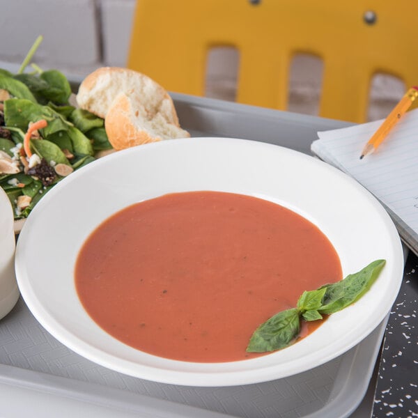 A tray with a Carlisle white polycarbonate soup bowl filled with red soup and a salad.