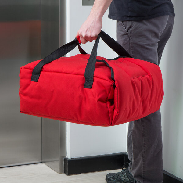 A man holding a red Cambro insulated pizza delivery bag.