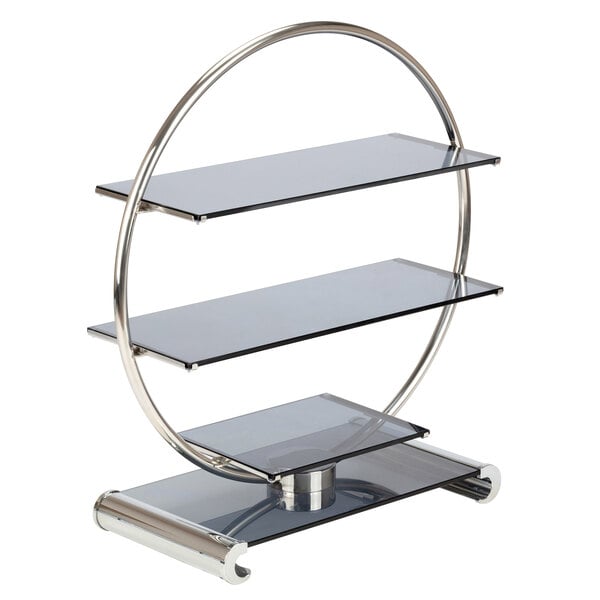 A Bon Chef stainless steel and glass wheel display stand with three glass shelves in a round metal frame.