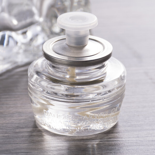 A close-up of a small glass bottle with a lid containing clear liquid.