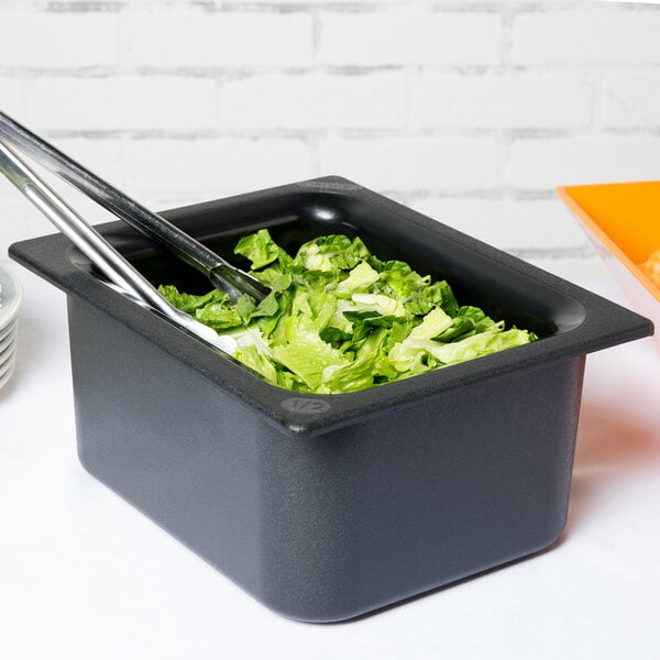 A Carlisle black plastic food pan filled with lettuce on a salad bar counter.