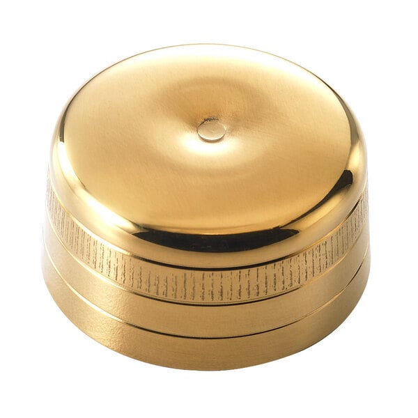 A gold-plated round cap for a cocktail shaker.