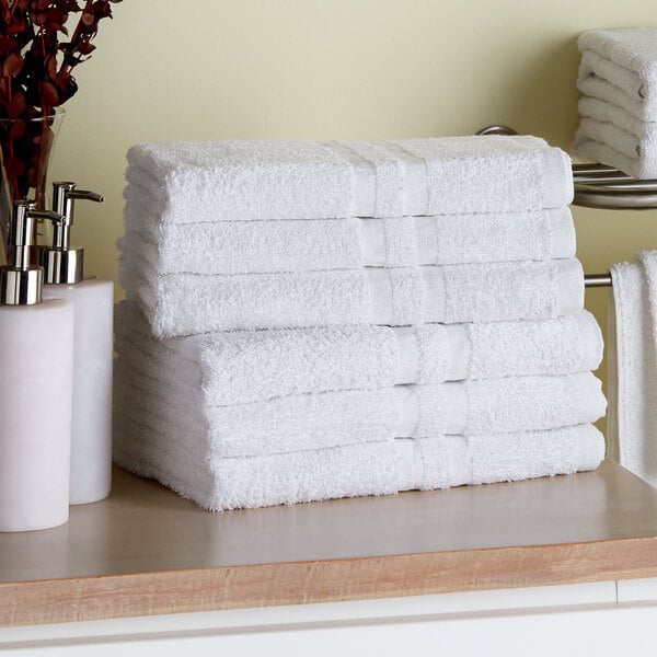A stack of white Lavex bath towels on a counter.
