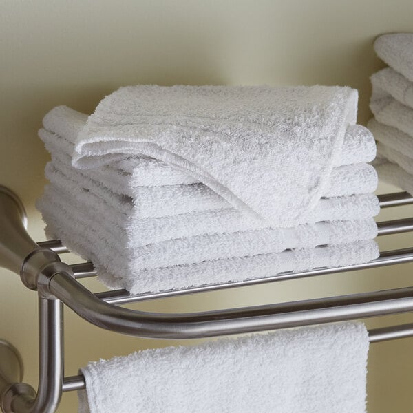 A stack of Lavex white wash cloths on a metal rack.
