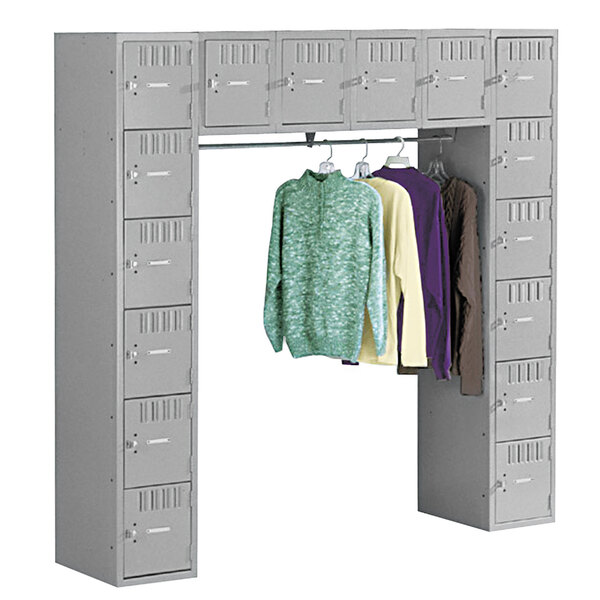 A close-up of a grey Tennsco steel locker with a coat bar and shirts hanging inside.