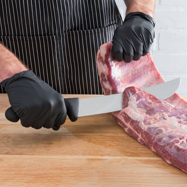 A person in black gloves using a Mercer Culinary cimeter knife to cut meat on a wooden surface.