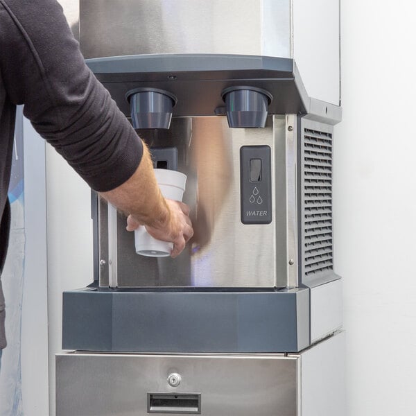 A person pouring water into a Scotsman Meridian ice and water dispenser.