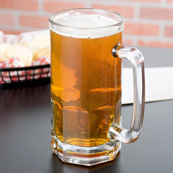 An Anchor Hocking glass beer mug filled with beer on a table.