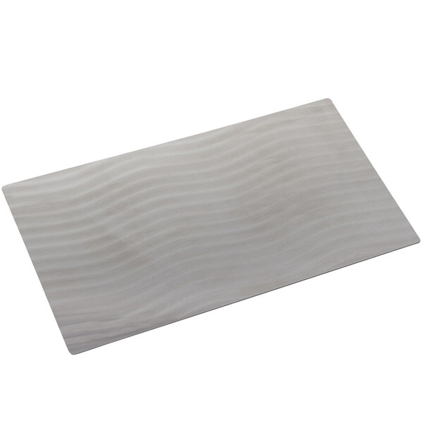 A stainless steel rectangular tile with wavy lines.
