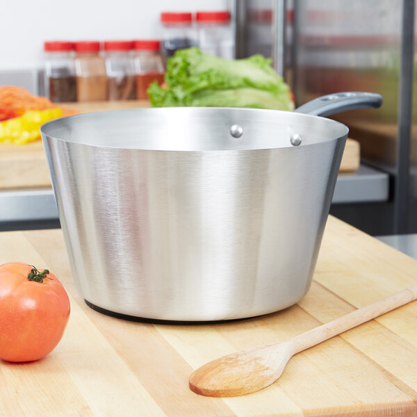 A Vollrath stainless steel sauce pan with a wooden spoon