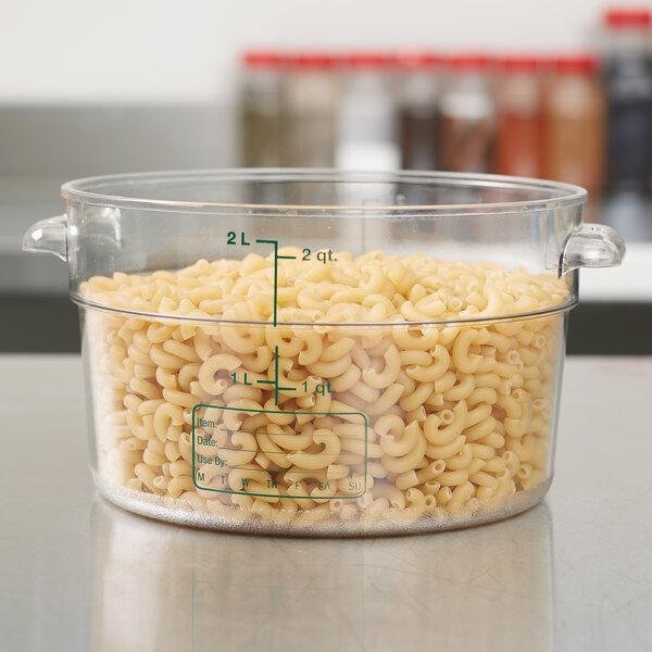 A clear Carlisle round food storage container filled with macaroni noodles.