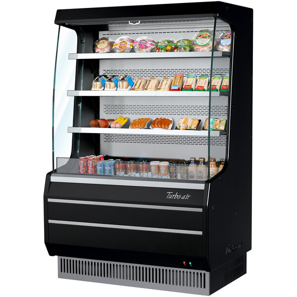 A Turbo Air black air curtain merchandiser with food on shelves in a room.