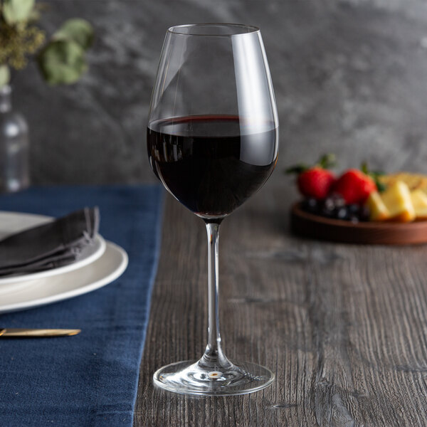A Spiegelau red wine glass on a table with a glass of red wine.