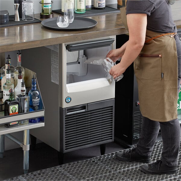 A woman pouring a glass of wine from a Hoshizaki undercounter ice machine.