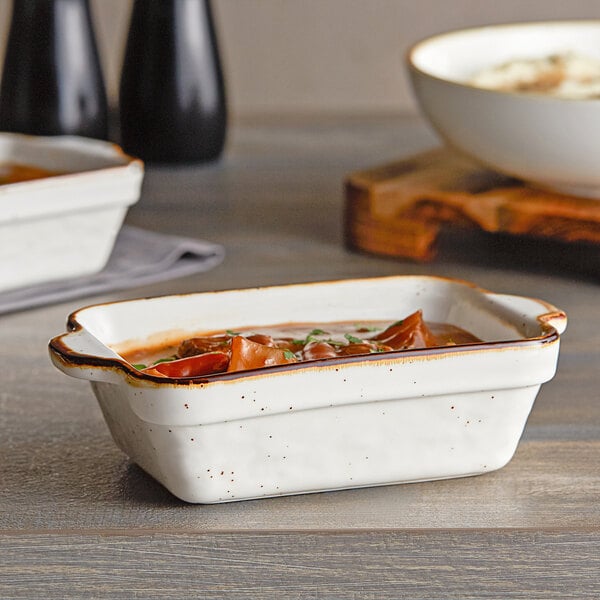 A white rectangular Acopa Keystone stoneware casserole dish with food in it.