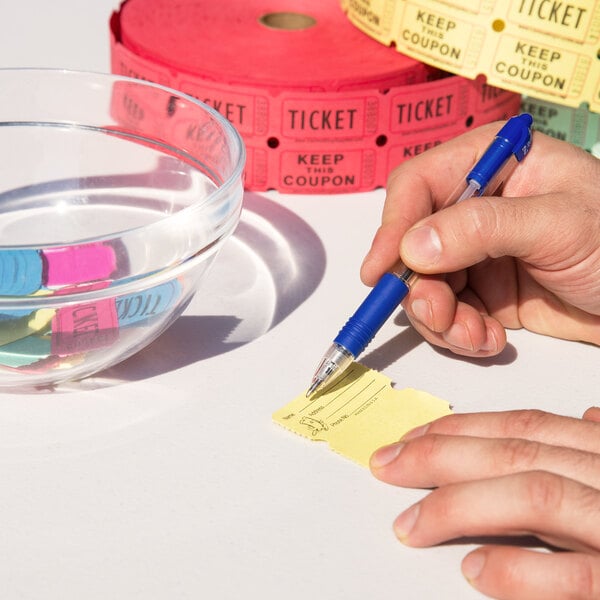 A person using a pen to write on a yellow Carnival King raffle ticket.