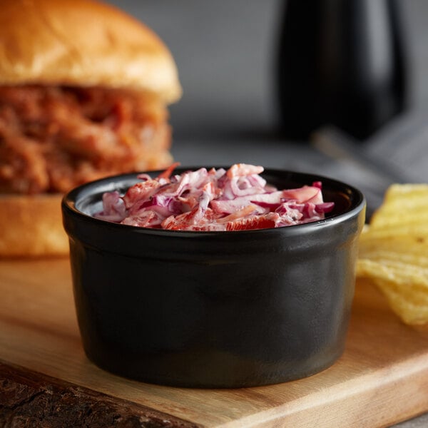 A table with a bowl of pulled pork and a bowl of coleslaw.