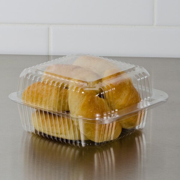 A Dart clear hinged PET plastic container with rolls of bread inside.