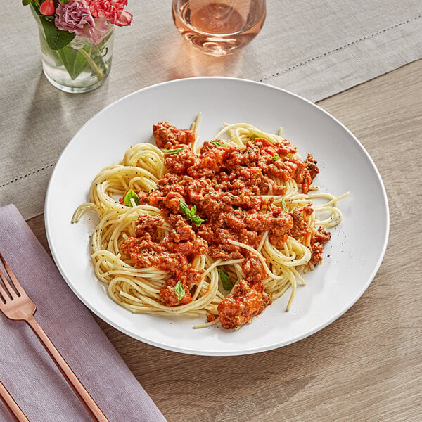 A plate of spaghetti with meat sauce and a fork on a white stoneware plate.