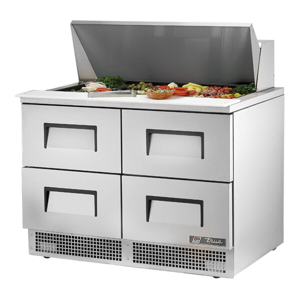 A True 48 1/8" 4 drawer refrigerated sandwich prep table with food on the counter.