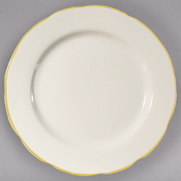 A CAC ivory china plate with a scalloped edge and gold trim.