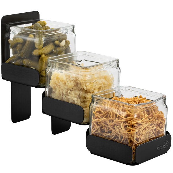 A Rosseto matte black 3-level condiment station with three glass containers filled with food.