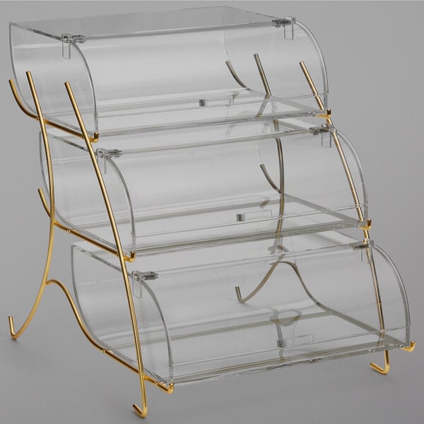 A Rosseto clear acrylic three-tier pastry display case with brass wire stand.