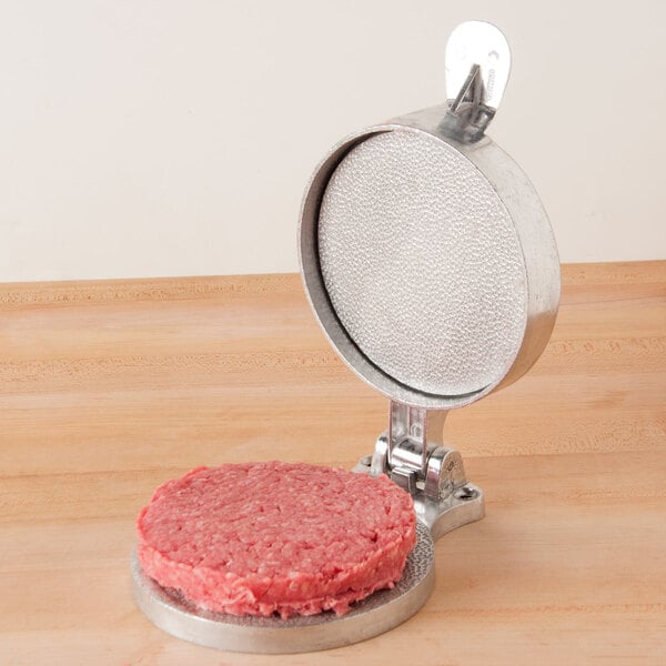 An American Metalcraft hamburger patty being pressed with a round metal container.