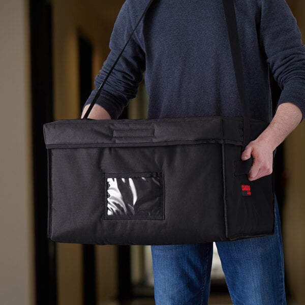 A man holding a large black Cambro Jumbo Delivery GoBag.