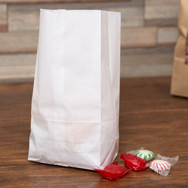 A Duro white paper bag filled with candy on a table.