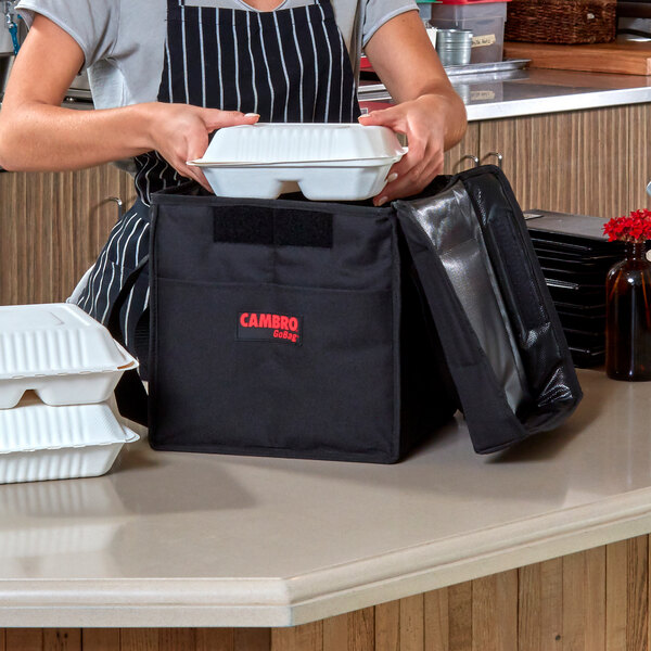 A woman in an apron putting food in a white Cambro container.