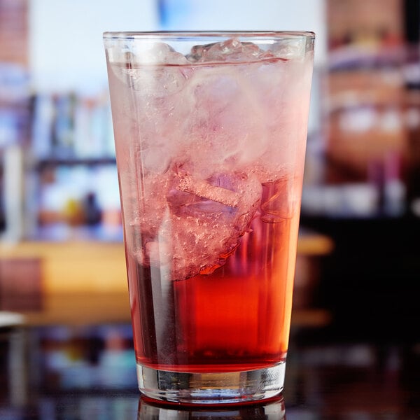 An Anchor Hocking mixing glass filled with a red drink and ice.