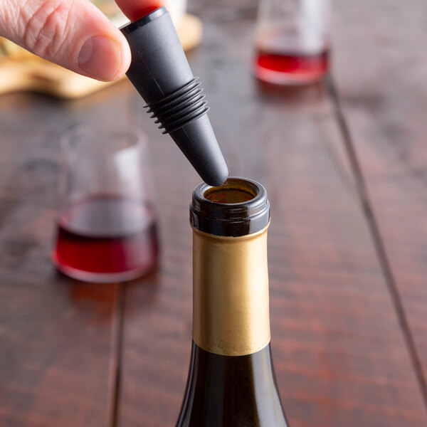 A person using a Franmara Flex Seal black wine stopper to seal a bottle of wine.