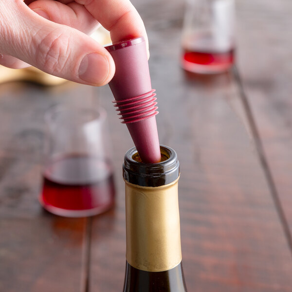 A person's hand using a Franmara Flex Seal Burgundy Wine Stopper to open a bottle of wine.