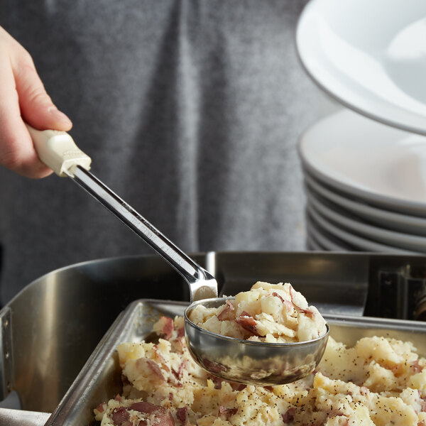 A person using a Vollrath Ivory Spoodle to serve mashed potatoes.